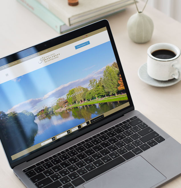 Diese Bild zeigt die neue CMS Website des Apart Hotel Haveltreff auf einem Laptop der neben einer Kaffeetasse auf einem Tisch steht und dient der Vorschau für den Webrelaunch des Apart Hotel Haveltreff durch die Marketingagentur Schweiger Design.